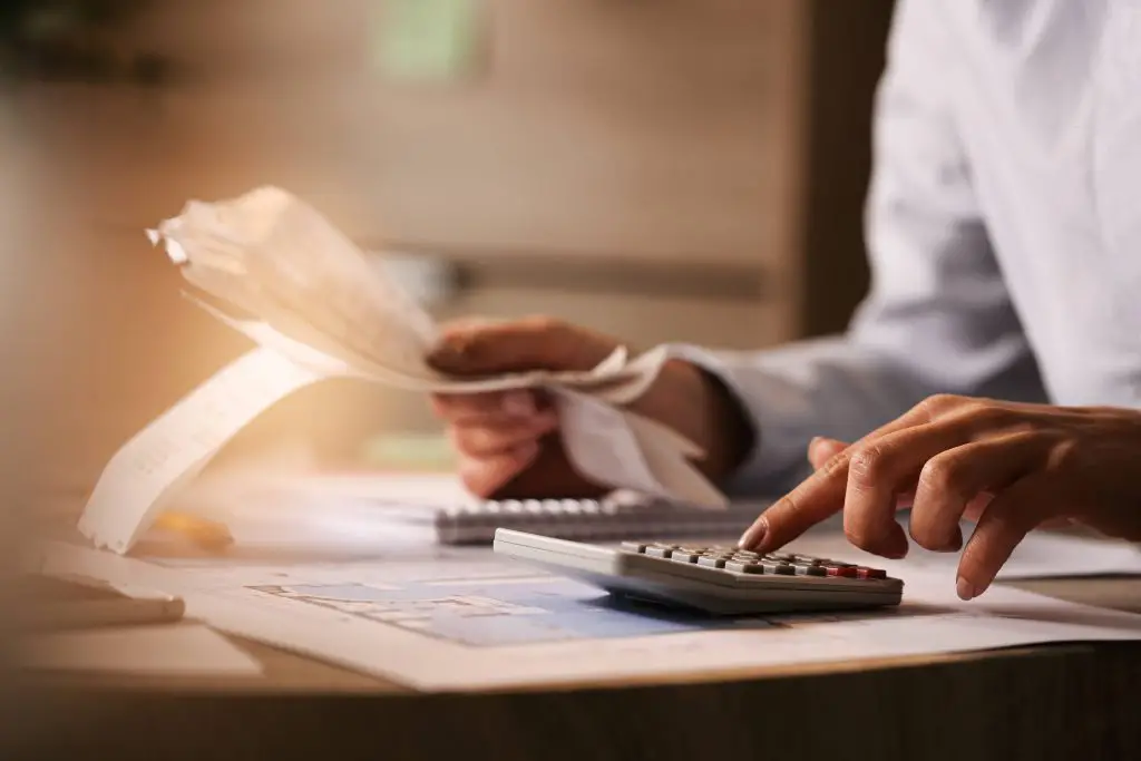 closeup economist using calculator while going through bills taxes office1